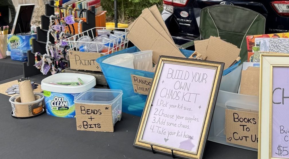 Paint, beads, cardboard, and other art supplies arranged on a table for a Build Your Own Chaos Kit at a Regulated Chaos Studio event. This was located at Off the Tracks Art Supply, LLC in DeKalb, Illinois.
